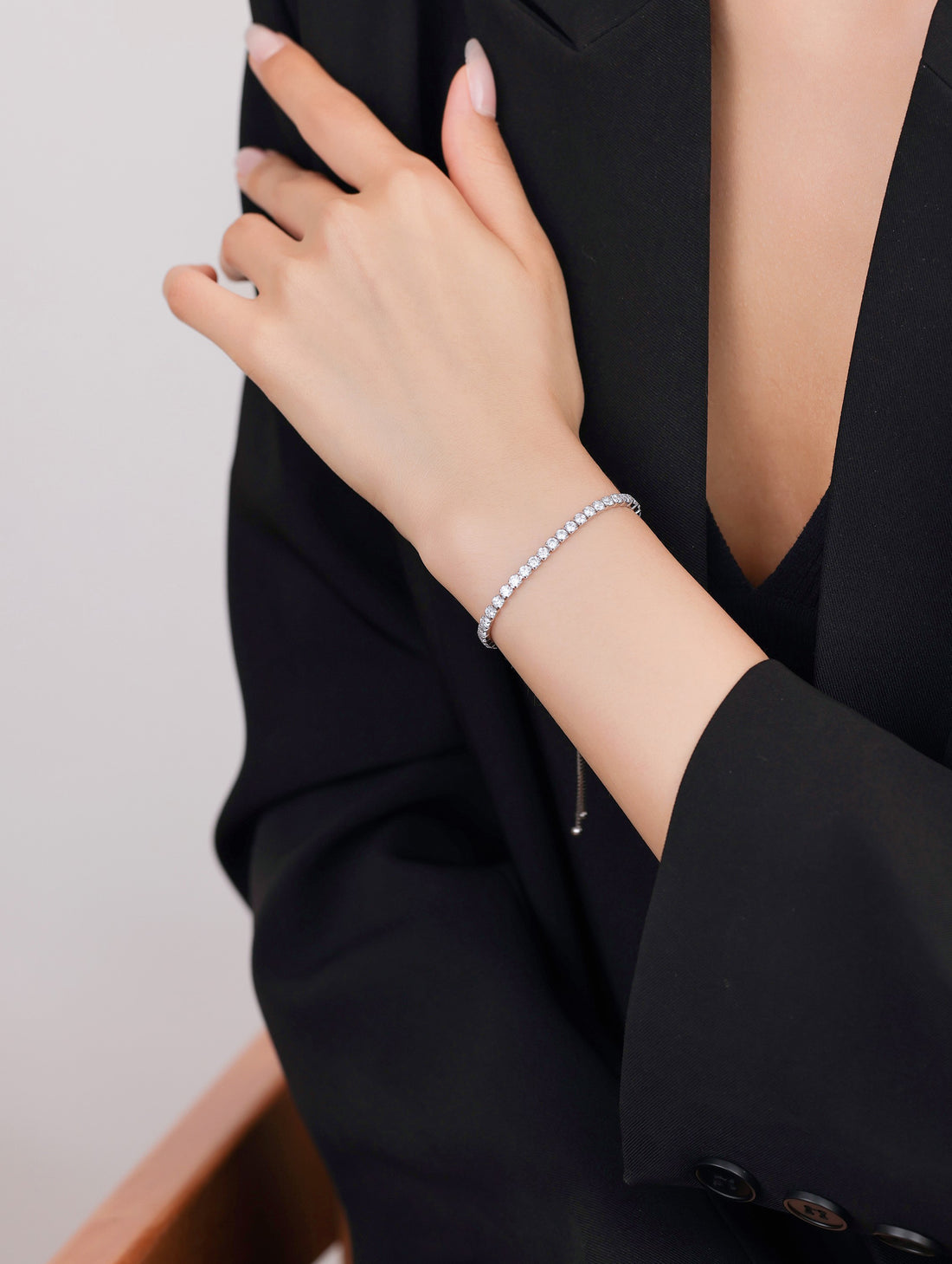 Silver bracelet with clear stones on a light pink surface