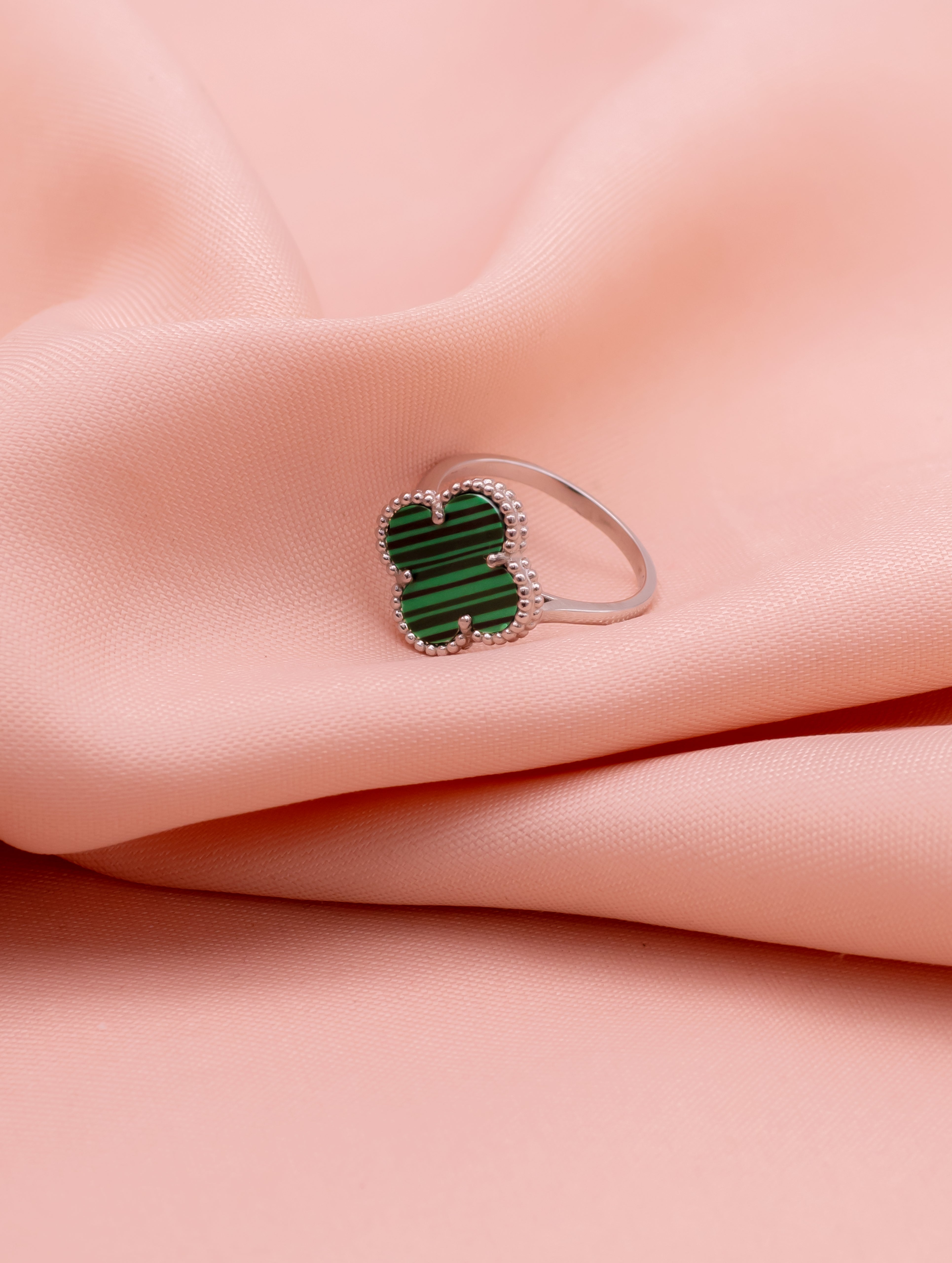 Ring with a green gemstone on a pink fabric background