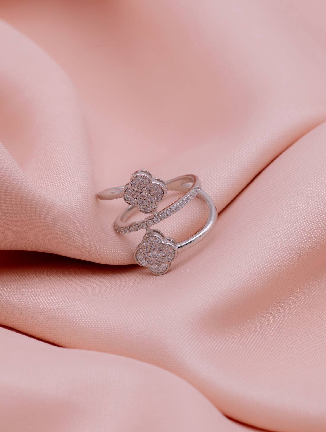 Silver ring with floral designs on a pink fabric background