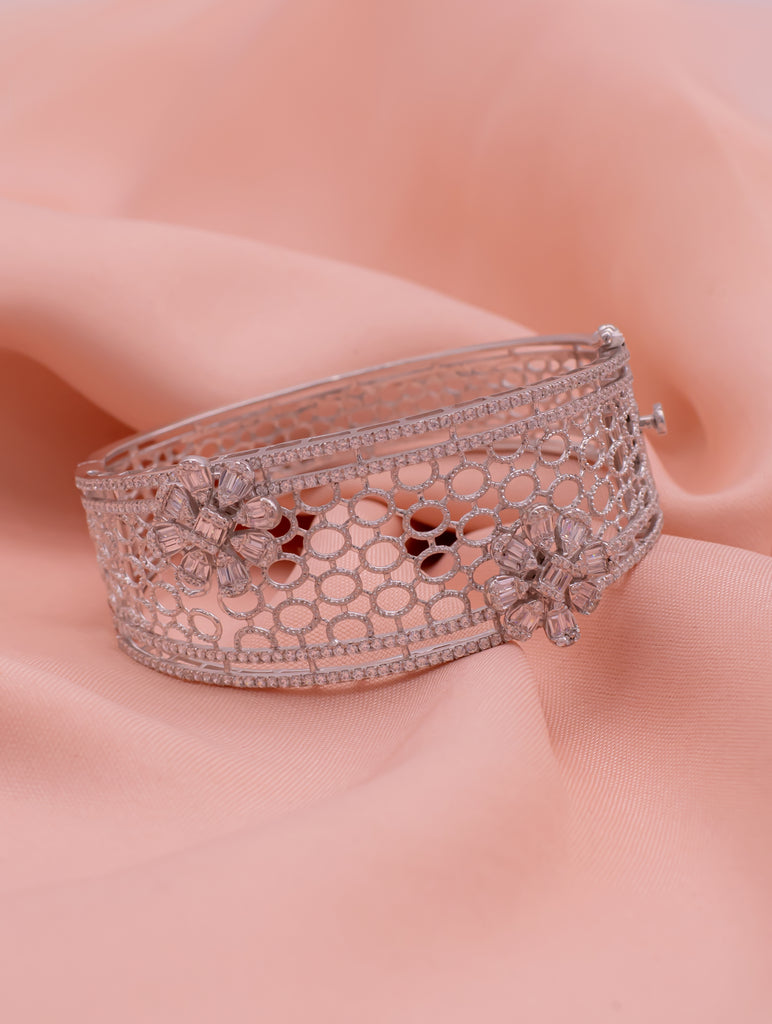 Rose gold bracelet with floral designs on a soft pink background