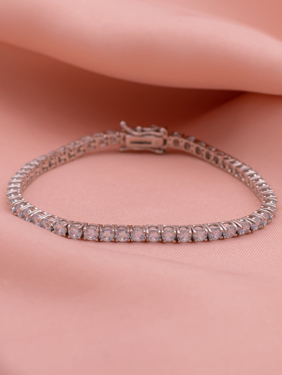 Silver bracelet with pink stones on a pink fabric background