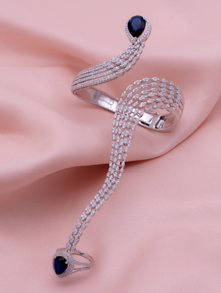 Silver snake-shaped ring with blue gemstones on a pink fabric background