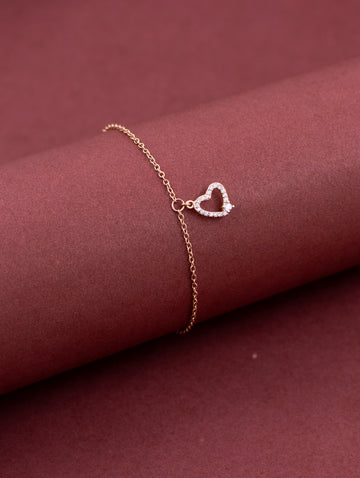 Rose gold bracelet with a heart-shaped clasp on a maroon fabric background