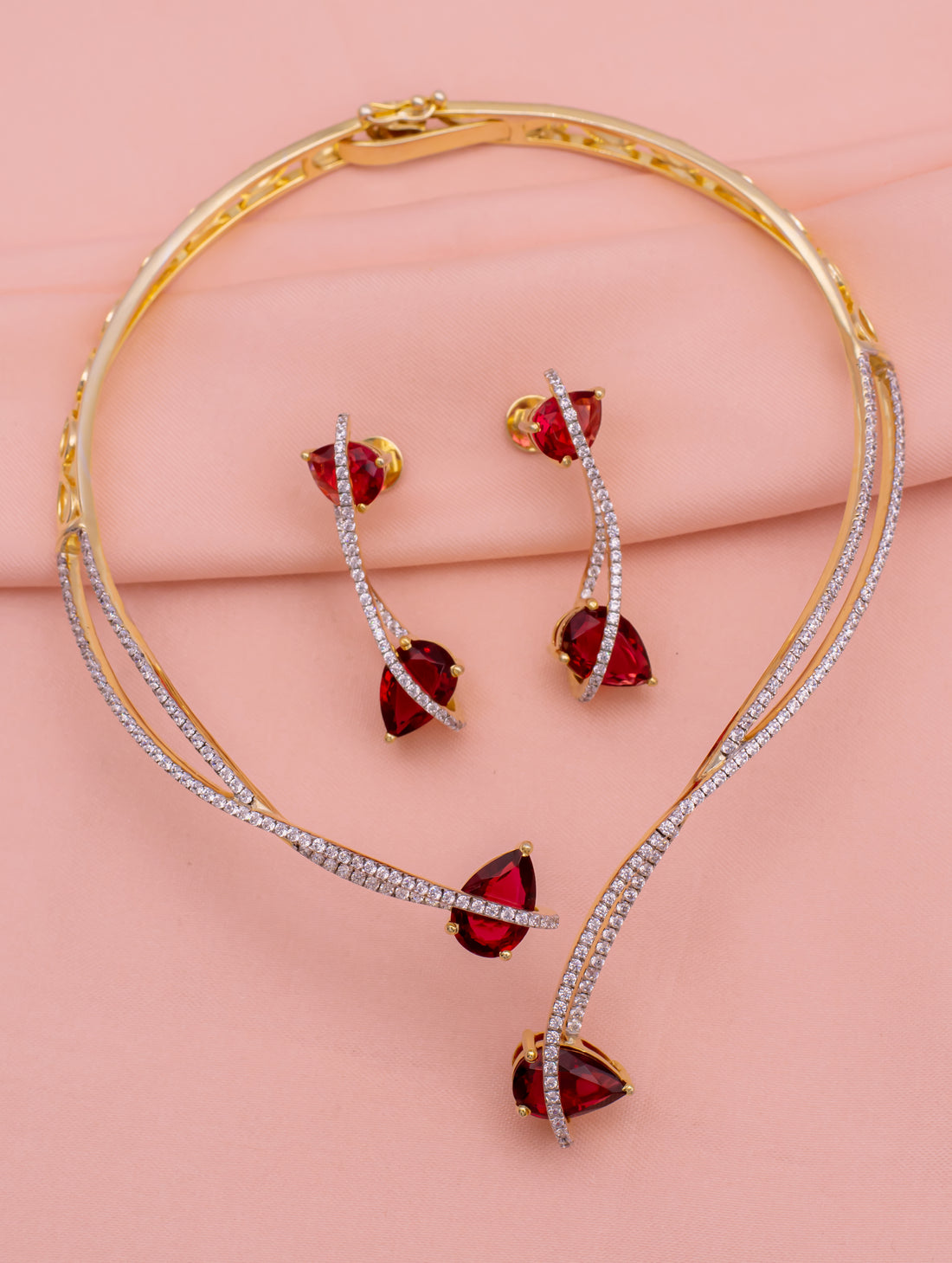 Jewelry set with red gemstones on a pink background
