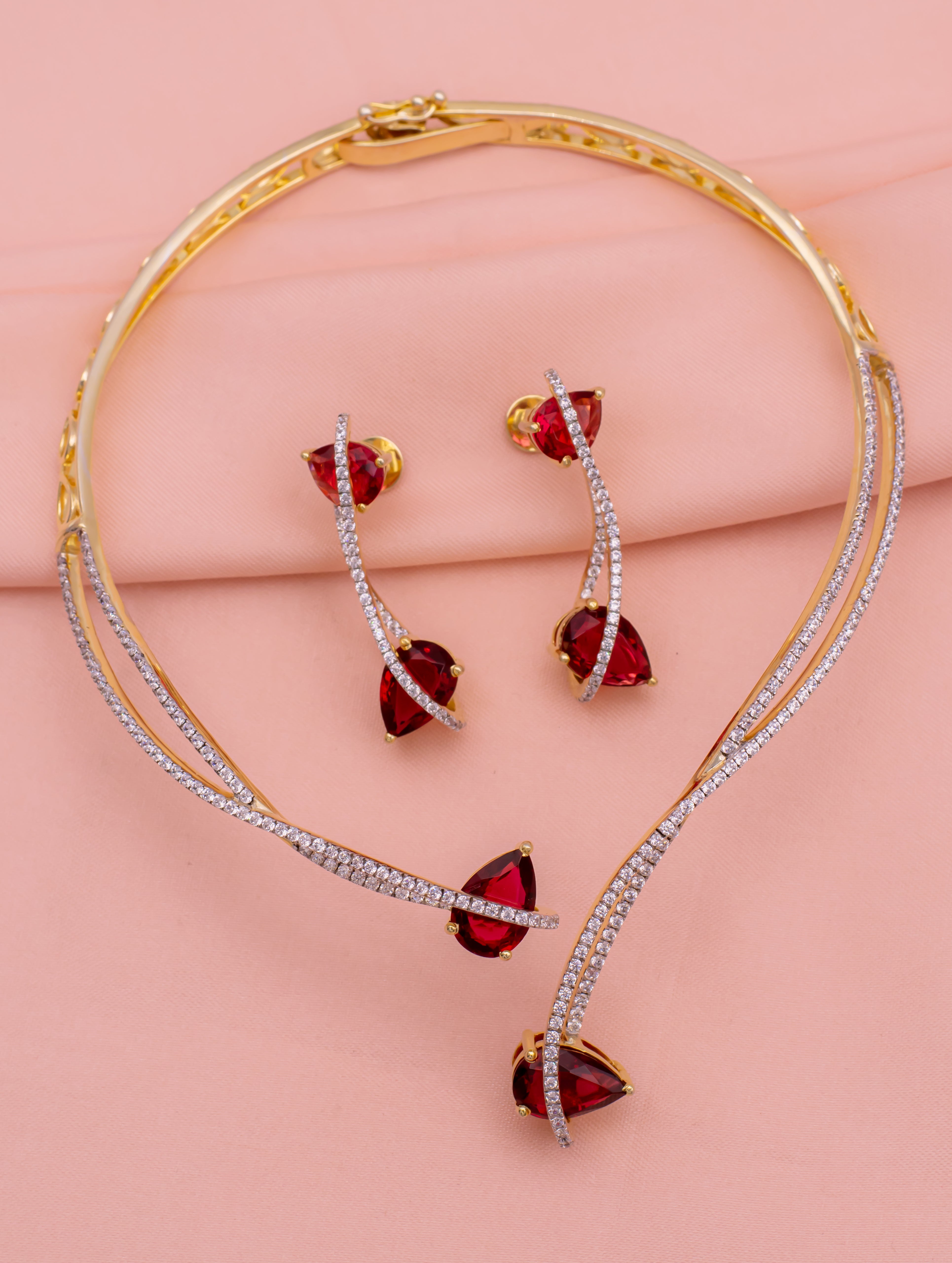 Jewelry set with red gemstones on a pink background